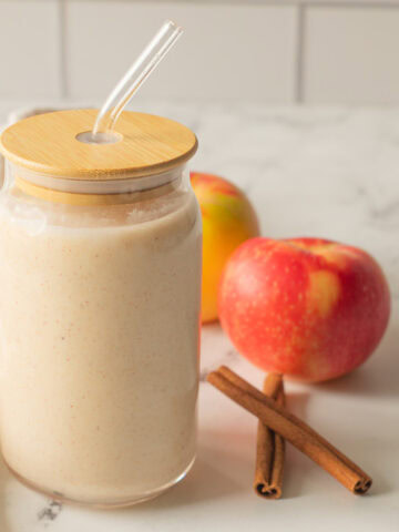 Apple cinnamon smoothie in a smoothie cup with straw.