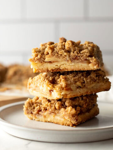 Stack of three apple pie bars on a plate.