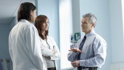 Three healthcare professionals standing in a clinical setting