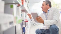 Pharmacy worker looking at shelves with medications on them