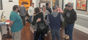 Individuals hugging and talking in a gallery setting