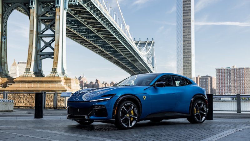 blue SUV sitting on cobblestone street in front of a large bridge