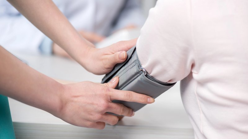 Nurse putting blood pressure monitor arm band on patient