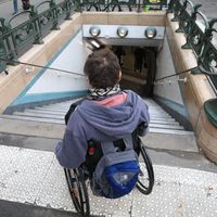 Personne en situation de handicap, devant une bouche de métro parisien (2020)