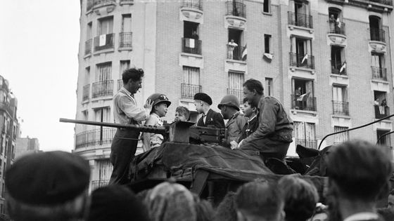 Des petits parisiens essaient le casque d'un soldat de la 2ème Division Blindée, devant la Mairie de Paris le 24 août 1944.