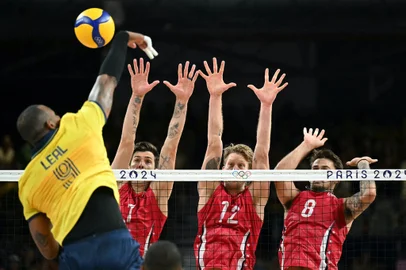 (Back LtoR) US' #01 Matthew Anderson, US' #12 Maxwell Holt and US' #08 Torey DeFalco jump to block the ball from Brazil's #09 Yoandy Leal Hidalgo during the volleyball men's quarter-final match between USA and Brazil during the Paris 2024 Olympic Games at the South Paris Arena 1 in Paris on August 5, 2024. (Photo by Natalia KOLESNIKOVA / AFP)<!-- NICAID(15833255) -->