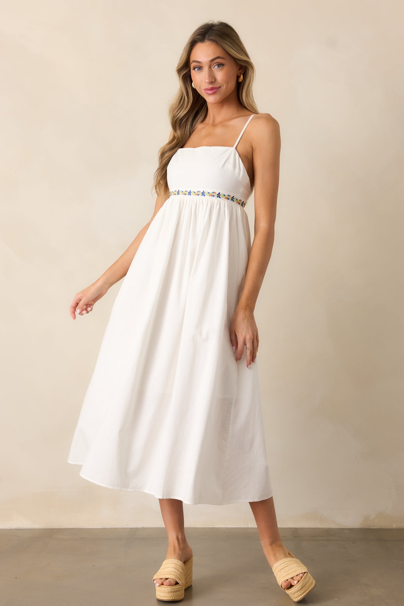 A full view of the ivory dress showcasing its square neckline, floral embroidered detailing, and relaxed skirt.