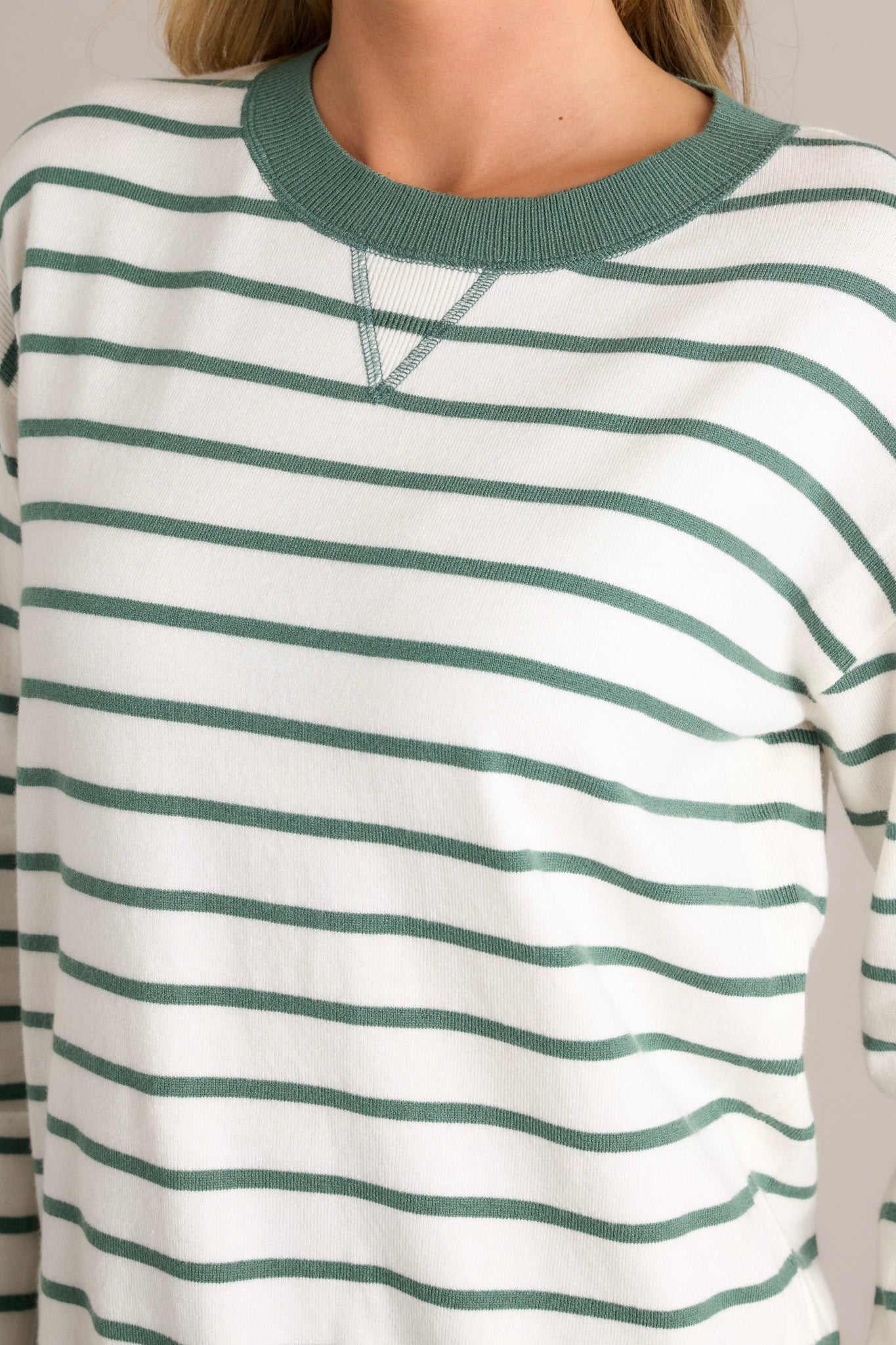 Close-up of the striped long sleeve top showing the rounded neckline, green horizontal stripe design, green trim, and long cuffed sleeves.