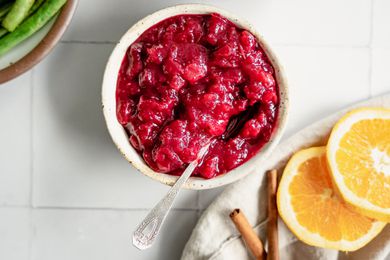 Instant Pot Cranberry Sauce Next to a Bowl of Green Beans and Table Napkin with Orange Slices and Cinnamon Sticks