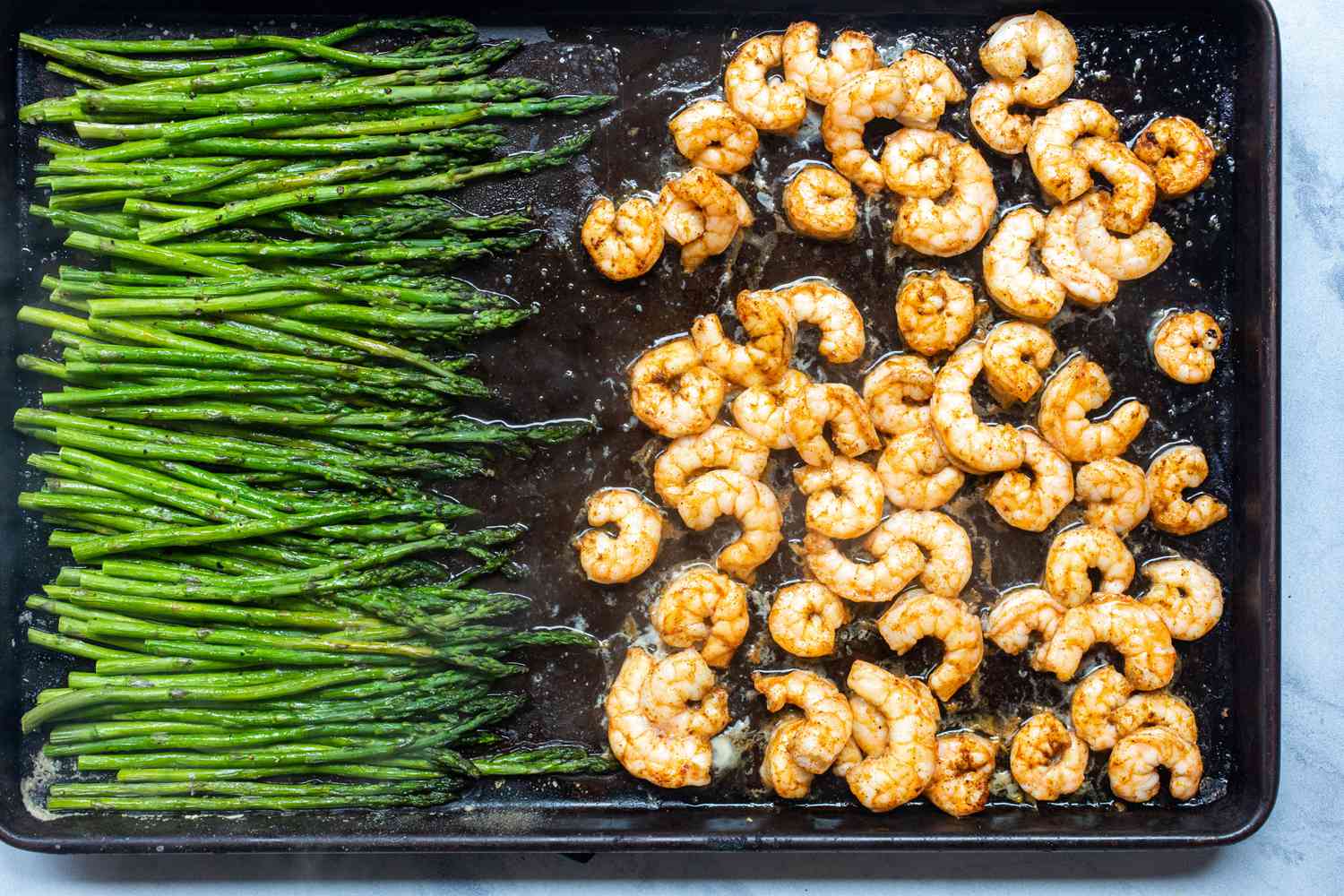 Overhead view of garlic butter sheet pan shrimp and asparagus on a baking sheet.