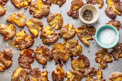 Smashed Potatoes and Two Small Bowls (One with Cracked Pepper and Another with Flaky Salt) on a Baking Pan 