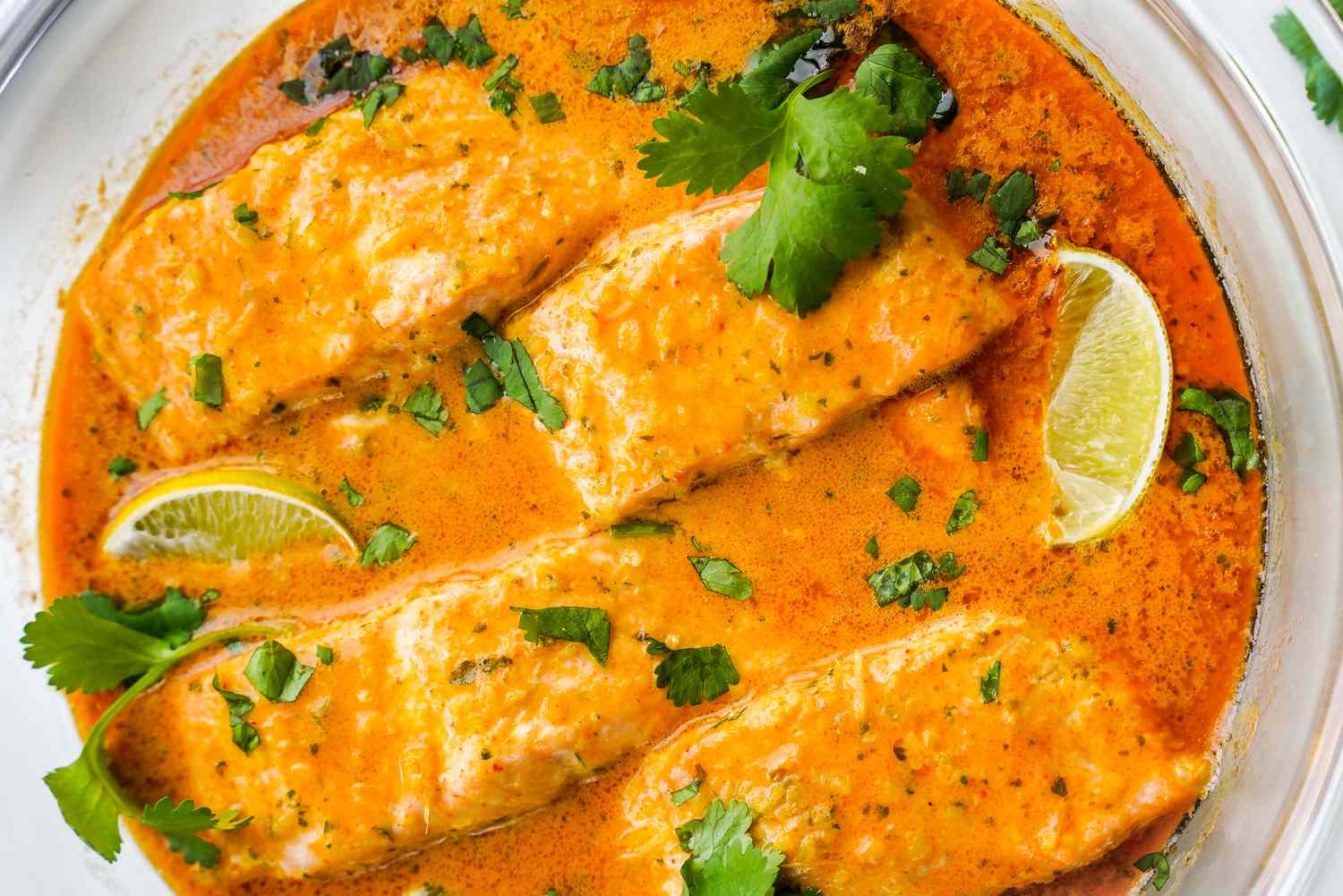 Microwave Red Curry Poached Salmon Topped with Cilantro and Lime Wedges in a Microwavable Glass Bowl