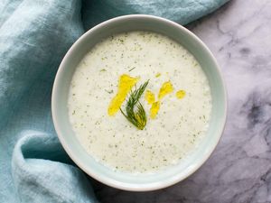 Cold Cucumber Soup in a pale blue bowl garnished with dill and olive oil