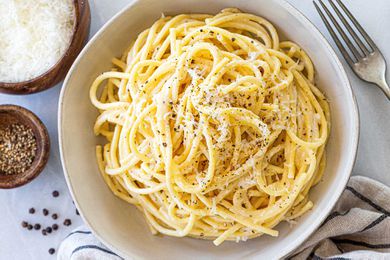 Cacio e Pepe with black pepper - spaghetti noodles in a white bowl with black pepper.