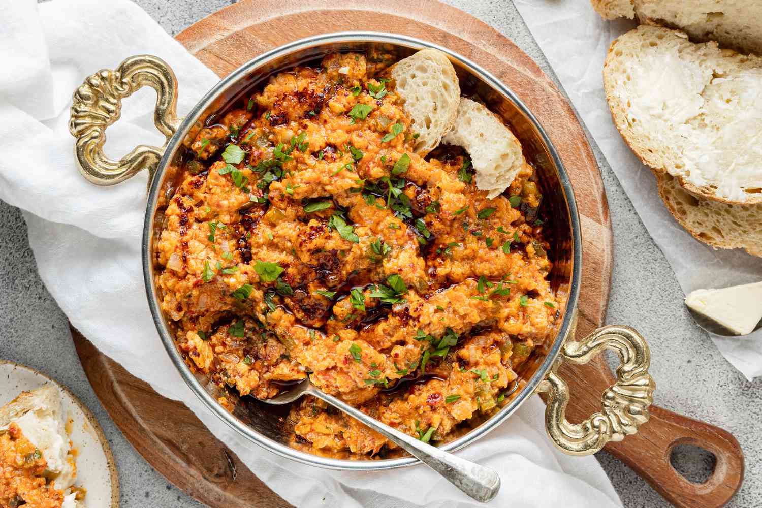 Menemen (Turkish Scrambled Eggs and Tomatoes) in a Pot with a Spoon, Surrounded by Some Slices of Bread and a Plate