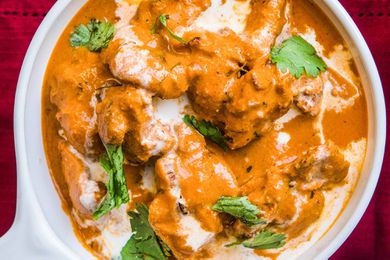 A dish of Butter Chicken garnished with cilantro leaves