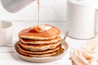 A stack of banana pancakes with syrup pouring over the top