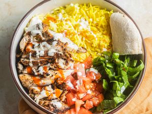  Bowl of Halal Cart-Style Chicken Over Rice Next to an Orange Kitchen Linen