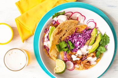 A plate of fish tacos with a glass of beer nearby