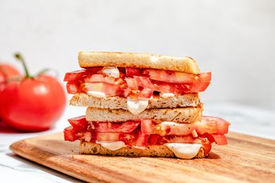 tomato sandwich (cut in half and stacked) on a cutting board