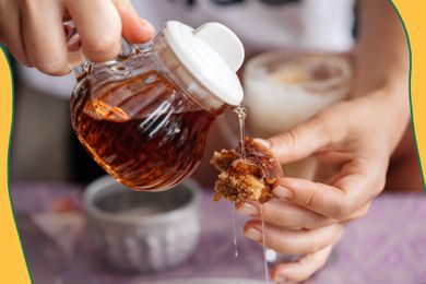 Photo of a person pouring maple syrup onto a piece of pancake (hand holding up the pancake piece) with yellow and blue wavy illustrations on the corners of the photo