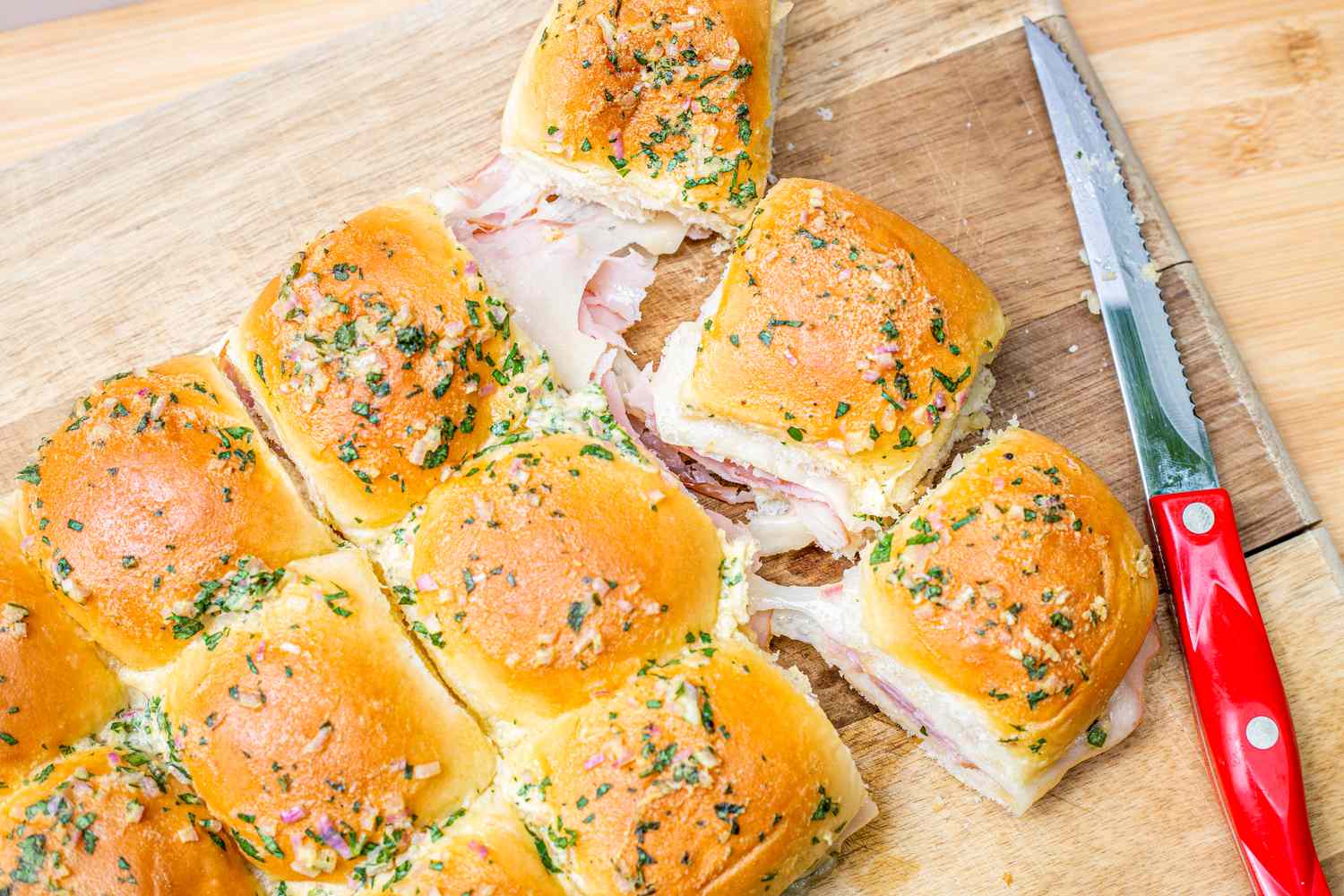 Hot Ham and Cheese Sandwiches on a Cutting Board with a Knife