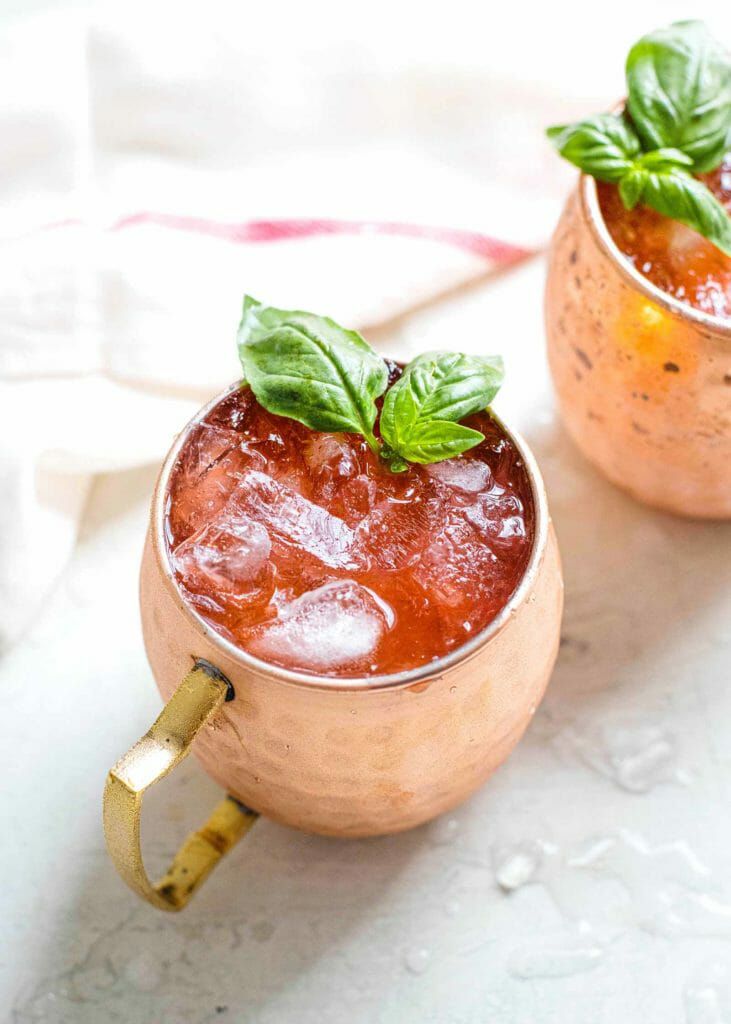 Strawberry and Basil Moscow Mule Cocktail red moscow mule with green basil garnish in copper mug