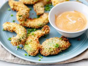 Air fryer avocado slices on a blue plate with dipping sauce