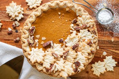 Decorating a pumpkin pie with leaves cut out of pie dough for Thanksgving family ideas.