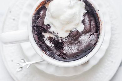 Overhead view of a brownie in a white mug topped with ice cream.