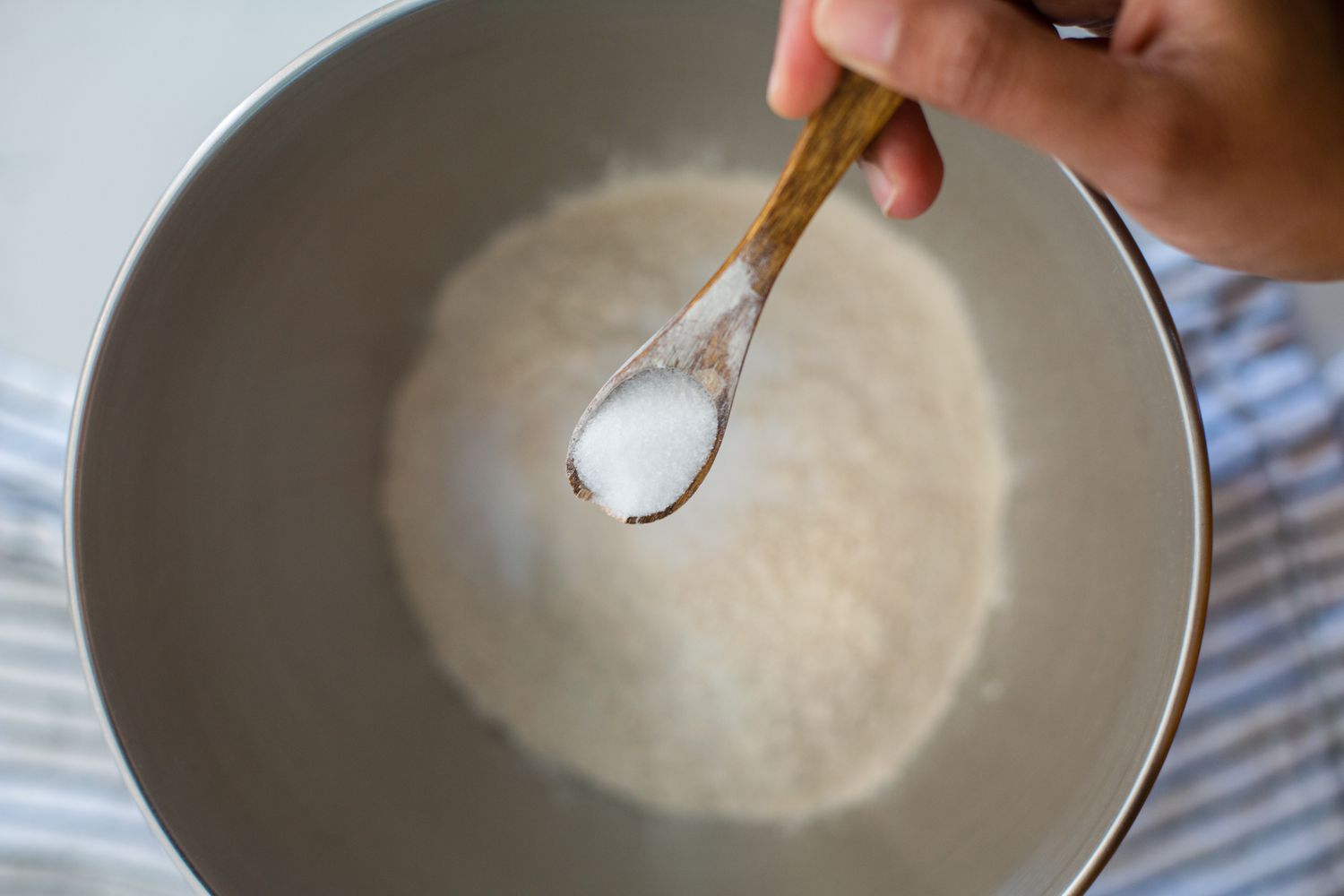 Adding ingredients to a bowl to make a roti recipe.