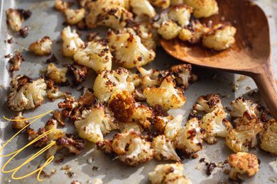 Photo of roasted cauliflower on a sheet pan with yellow-lined illustrations on the corner