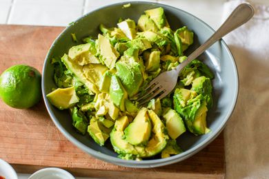 Avocado slices in a bowl with a fork to make guacamole