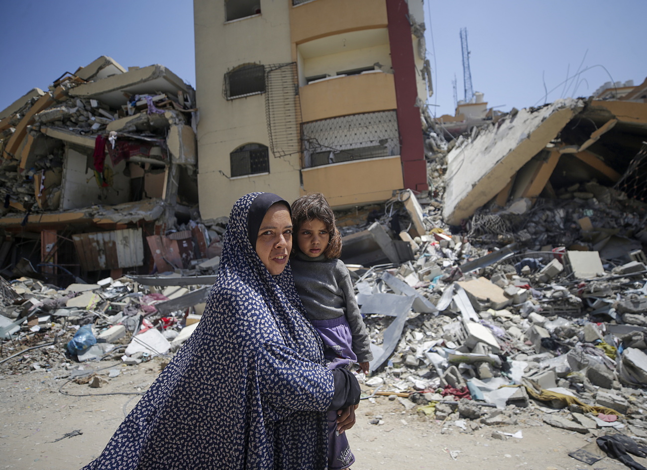 Picture of a woman holding a child in Gaza with rubble in the background