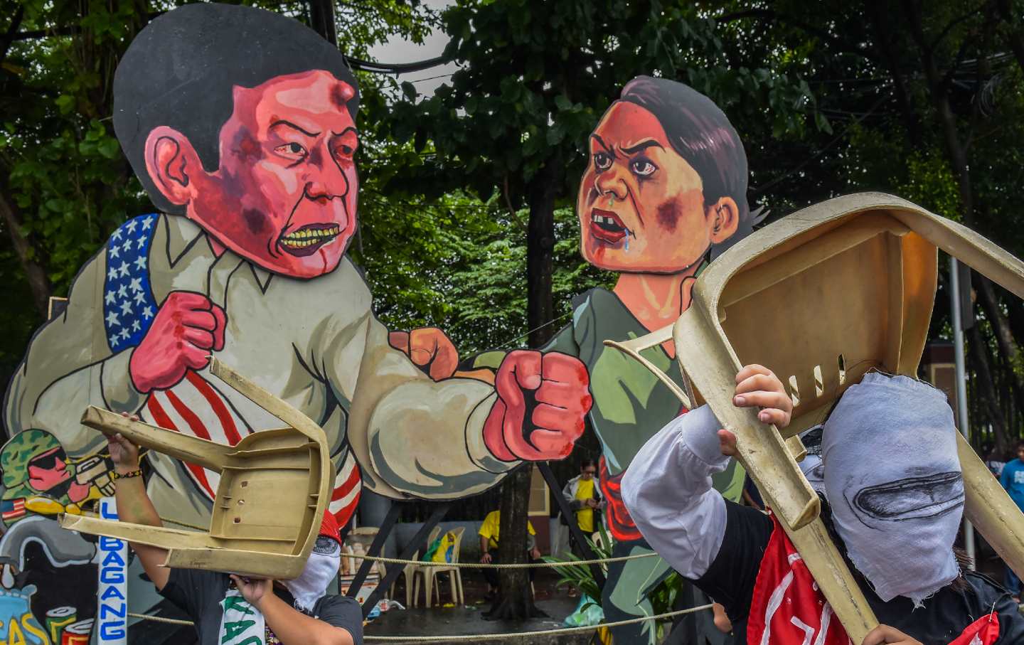 Masked protesters act in front of the effigy of President Marcos Jr. and Vice President Sara Duterte at Commonwealth Avenue during the demonstration.