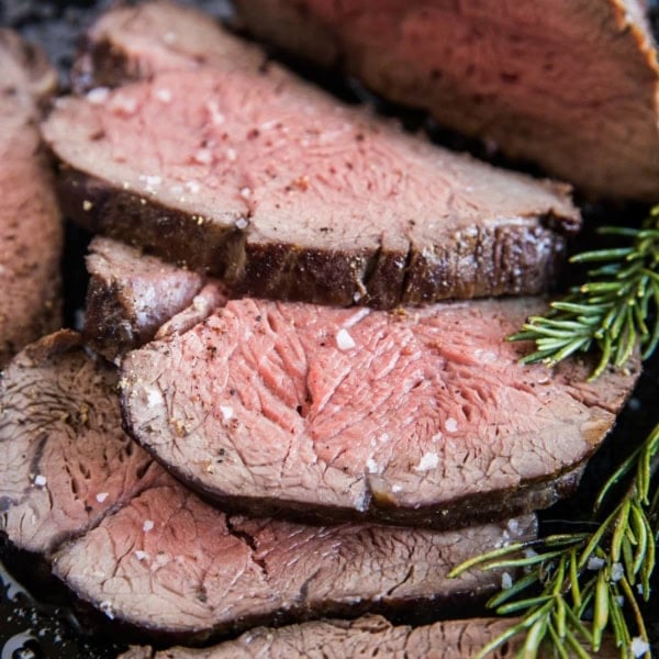 Medium-rare beef tenderloin sliced into slices in a cast iron skillet