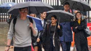 People shelter under umbrellas in Leeds. Low pressure will lead to even worse weather in parts of northern England this weekend