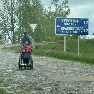 Volunteers push the disabled across the last stretch of their journey to safety