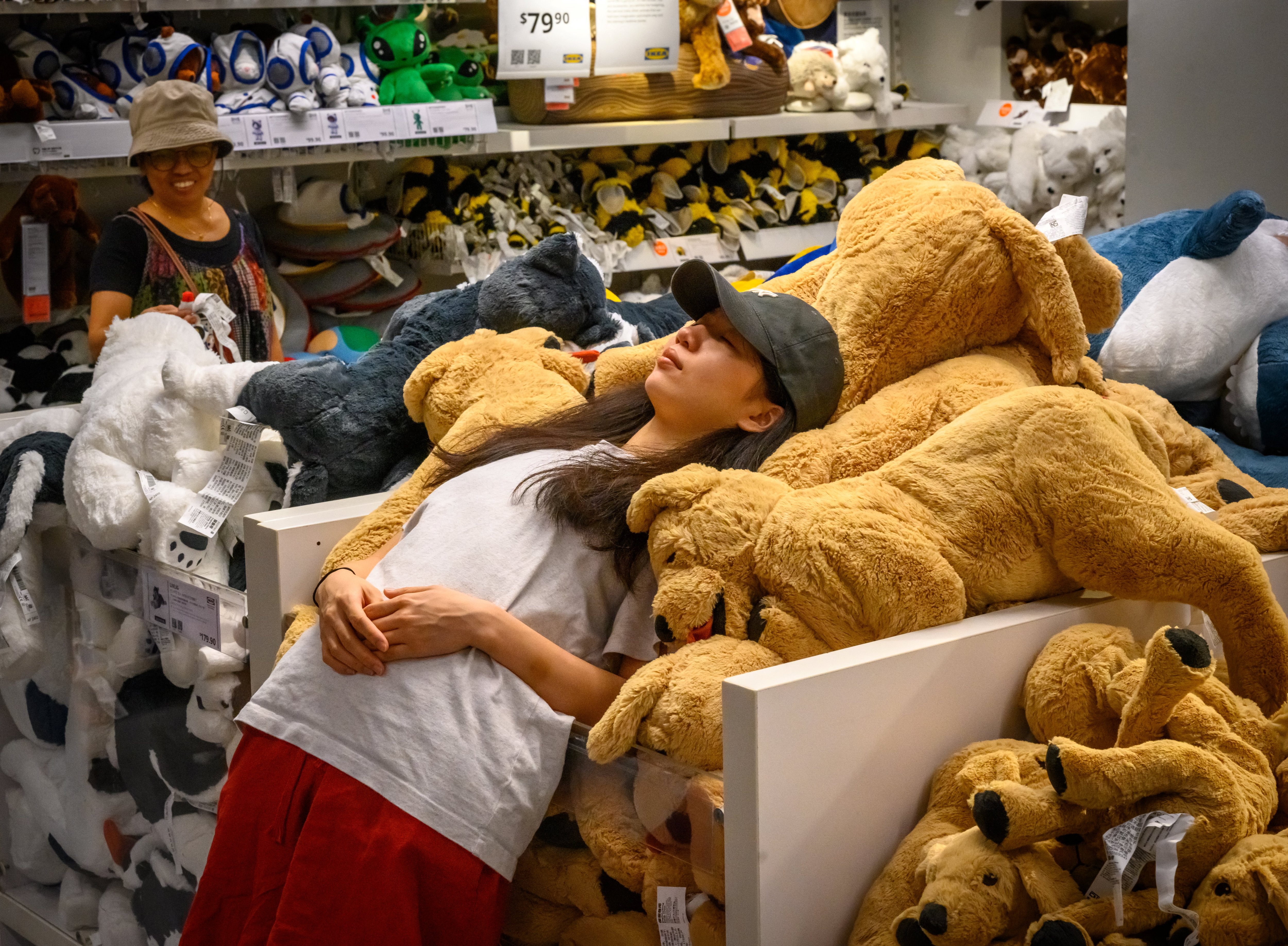 A woman gets comfortable on a pile of plush toys at an Ikea sleepover in the Causeway Bay shopping district of Hong Kong