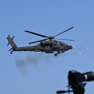 A US soldier watches as a South Korean Apache helicopter fires rockets during joint exercises at the Rodriguez Live Fire Complex in Pocheon