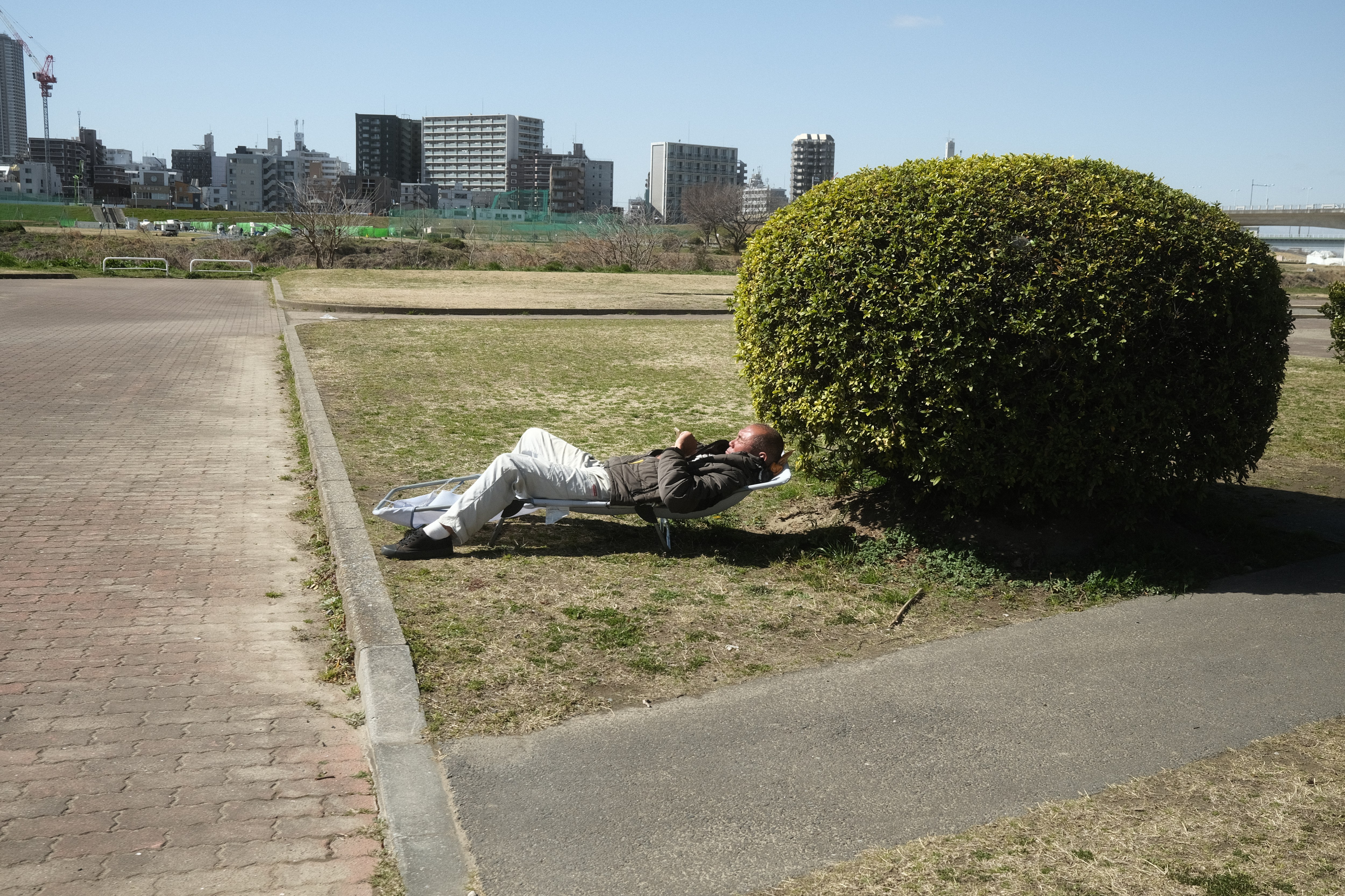 Man sunbathing in a park in Kokyo-mae Hiroba