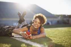 Student listening to mp3 player in grass