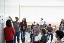 High school students giving presentation whiteboard in classroom