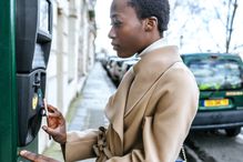 France, Paris, Young woman paying with her smartphone at parking automat
