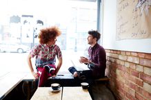 Two friends chatting in coffee shop window.