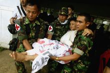 Men wearing red cross symbols carry an injured girl