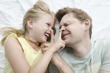 Father happy smiling daughter in bed - stock photo