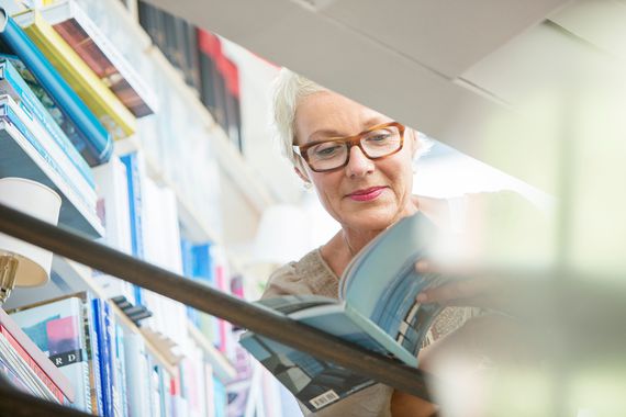 older woman looking through a book in a bookstore or library