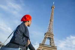 France, Paris, young woman wearing red beret in front of Eiffel Tower