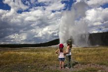 Two young girls watch as Old Faithful is Erupting